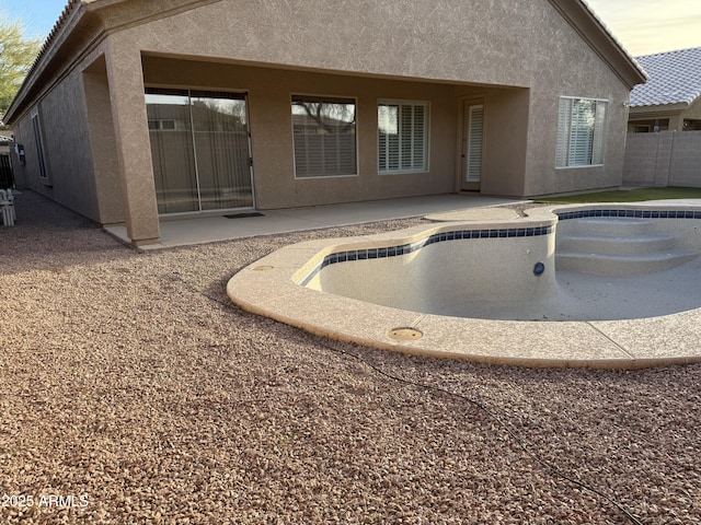 rear view of property featuring an empty pool and a patio