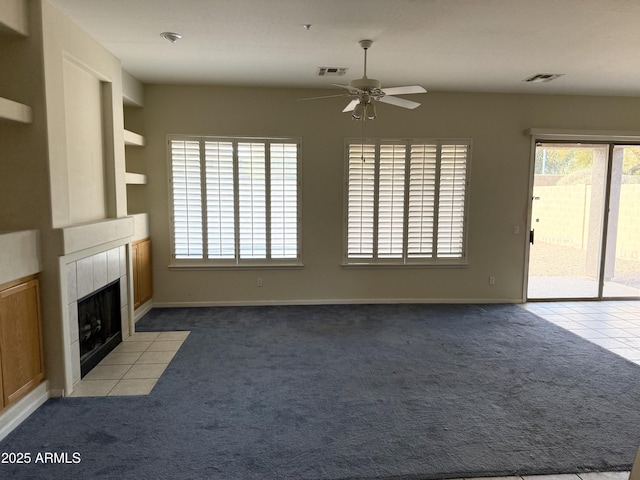 unfurnished living room featuring a tile fireplace, light carpet, and ceiling fan