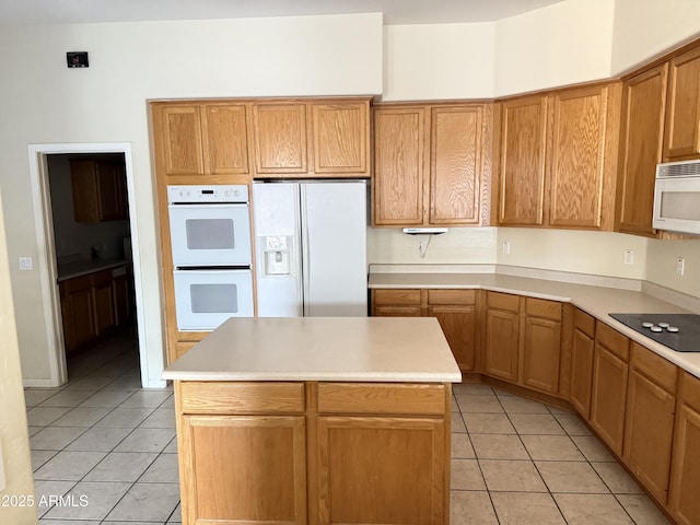 kitchen with white appliances, a kitchen island, and light tile patterned floors