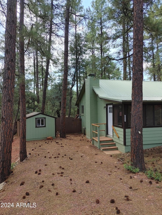 view of front of property with a shed, a chimney, metal roof, and an outbuilding