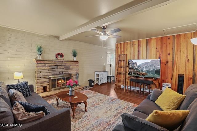 living room with dark wood-style floors, beam ceiling, attic access, ceiling fan, and a stone fireplace