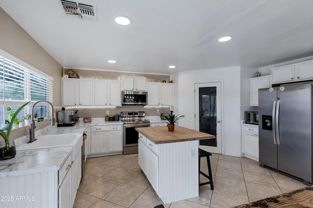 28014 N Jade St, San Tan Valley, AZ 85143 - kitchen featuring white cabinetry, stainless steel appliances, a center island, butcher block counters, and visible vents