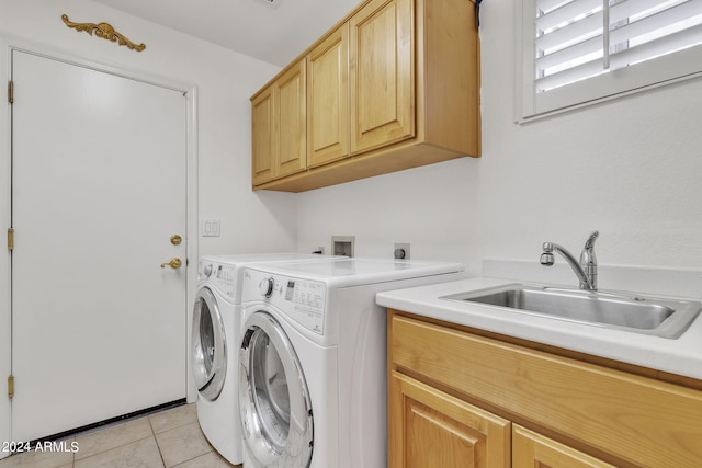 clothes washing area featuring cabinets, sink, washer and clothes dryer, and light tile patterned floors