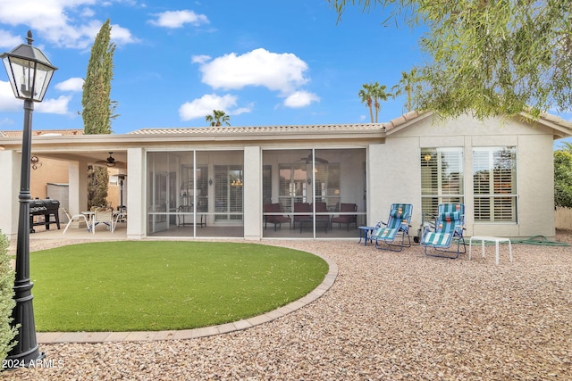 back of property featuring a yard, ceiling fan, a patio, and a sunroom