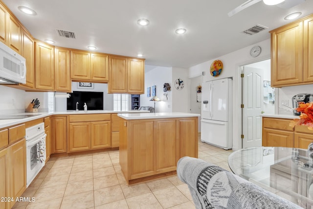 kitchen with a kitchen island, kitchen peninsula, light tile patterned floors, light brown cabinetry, and white appliances