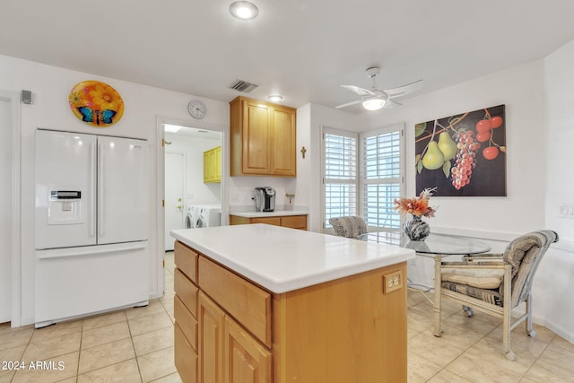 kitchen featuring white fridge with ice dispenser, a kitchen island, washer and clothes dryer, ceiling fan, and light tile patterned floors