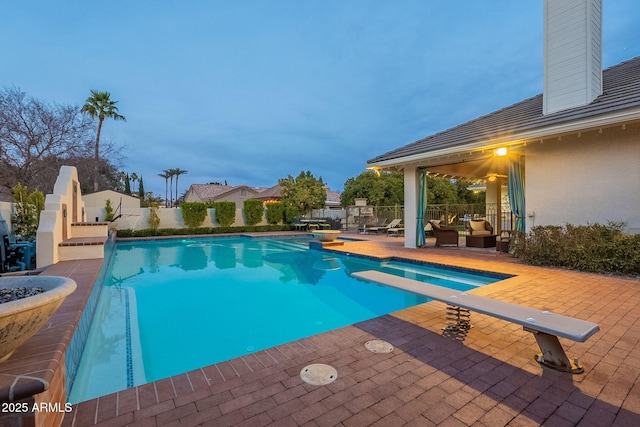 view of pool with a patio area and a diving board