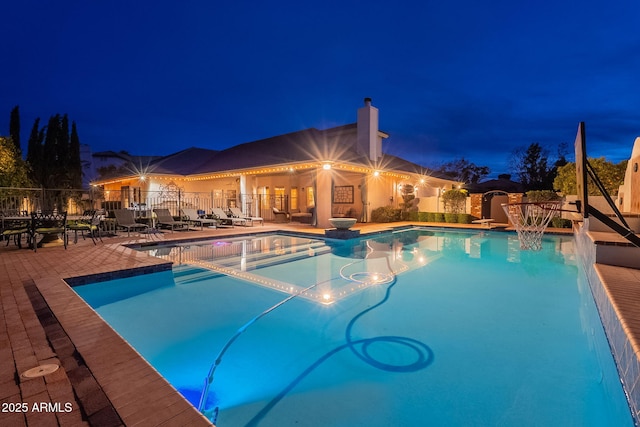 pool at night with a patio area