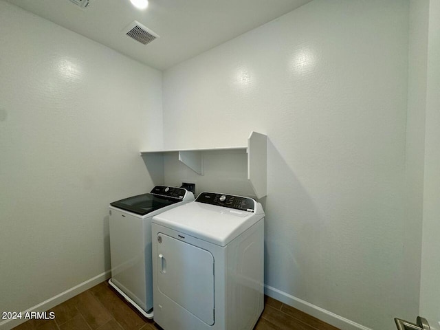 laundry room with washing machine and clothes dryer and dark wood-type flooring