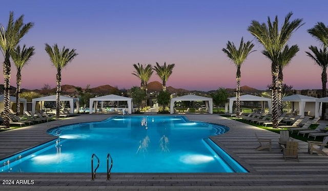 pool at dusk featuring a gazebo and a patio area