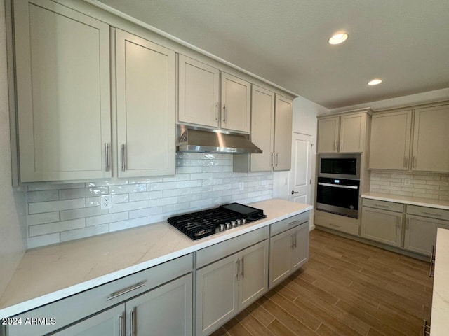 kitchen featuring tasteful backsplash, gray cabinetry, dark wood-type flooring, and appliances with stainless steel finishes