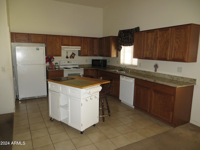 kitchen with light tile patterned floors, sink, a high ceiling, a center island, and white appliances