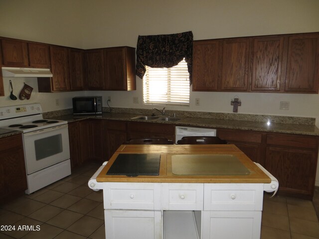 kitchen with white appliances, sink, a kitchen island, white cabinetry, and light tile patterned floors