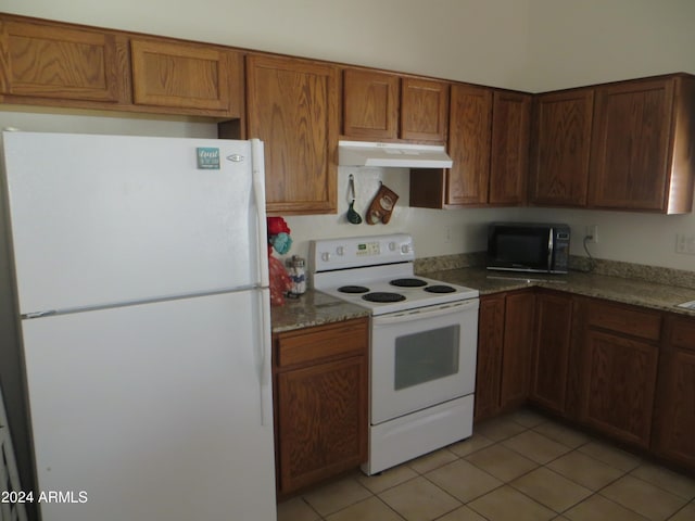 kitchen with white appliances, light tile patterned flooring, and dark stone counters