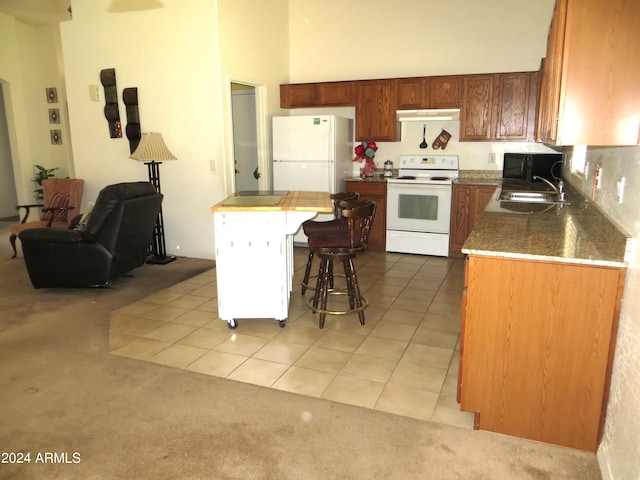 kitchen featuring white appliances, a breakfast bar area, a kitchen island, sink, and tile patterned flooring