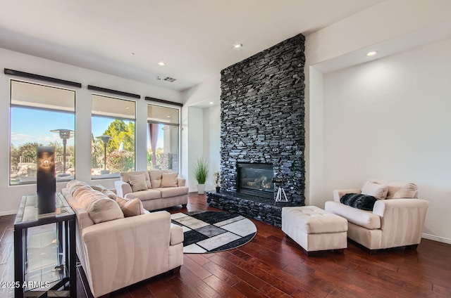 living room featuring a stone fireplace and dark hardwood / wood-style flooring