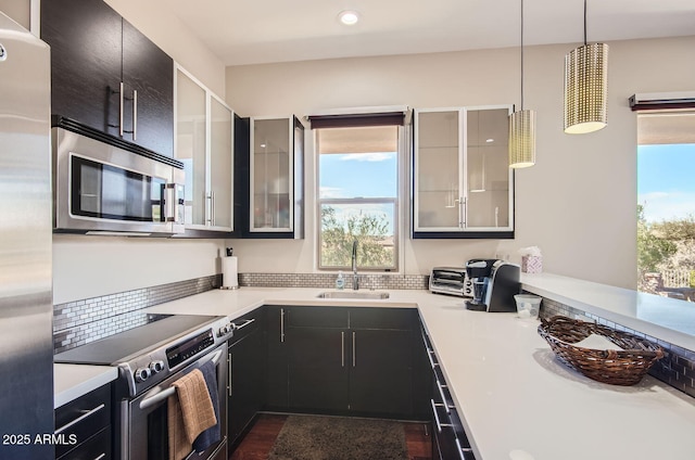 kitchen with appliances with stainless steel finishes, pendant lighting, and sink