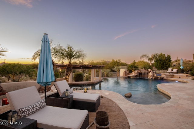 pool at dusk with pool water feature and a patio