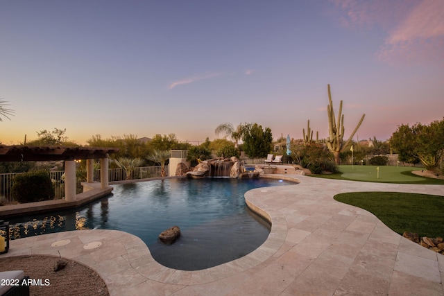 pool at dusk with pool water feature and a patio area