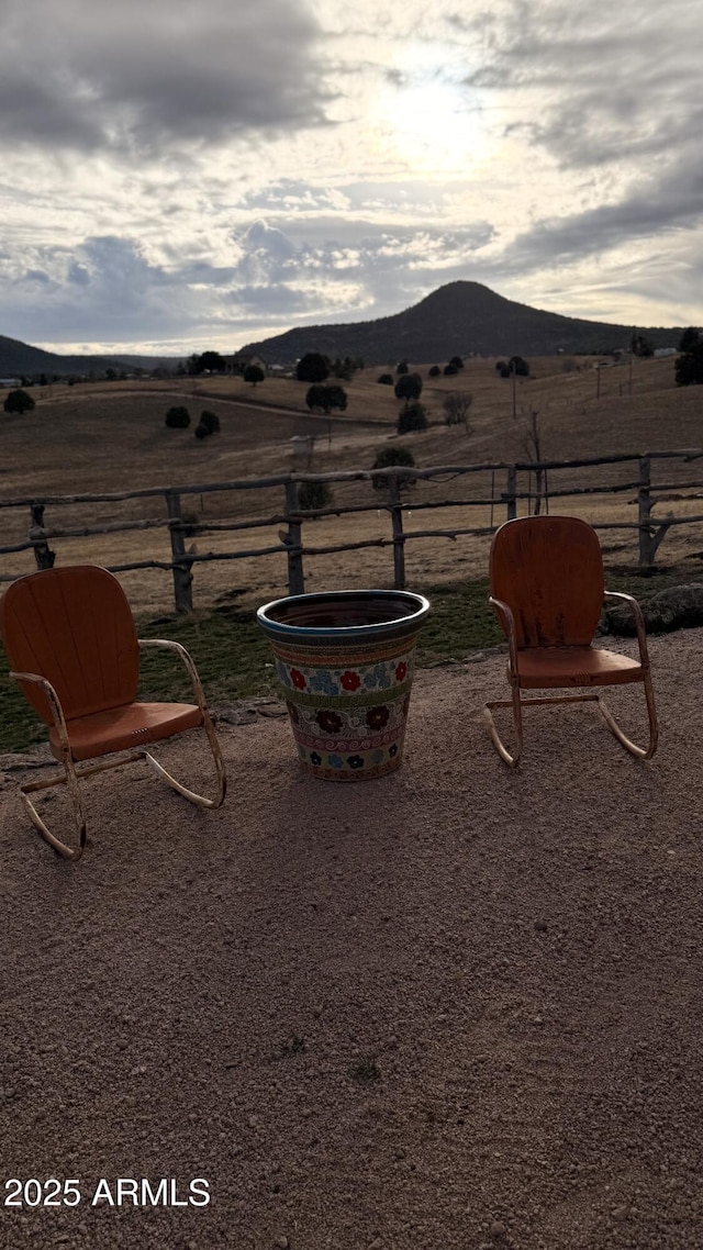 view of yard featuring a rural view, fence, and a mountain view