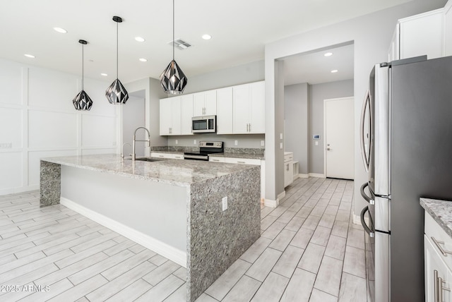 kitchen with white cabinetry, a kitchen island with sink, visible vents, appliances with stainless steel finishes, and a sink