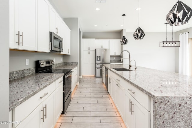 kitchen with a sink, white cabinetry, light stone counters, and stainless steel appliances