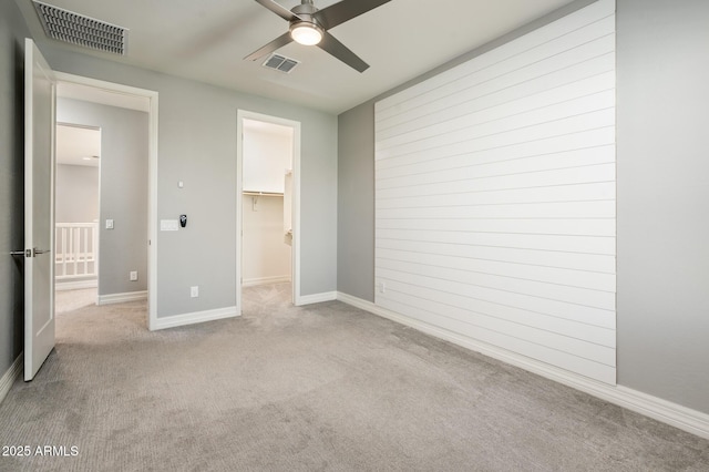 unfurnished bedroom with carpet flooring, baseboards, a spacious closet, and visible vents