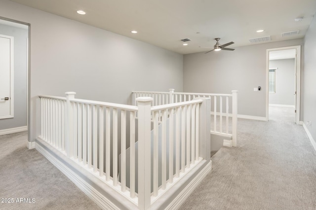 hallway featuring an upstairs landing, visible vents, and carpet