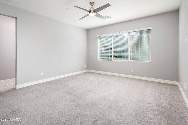 carpeted empty room with visible vents, baseboards, and a ceiling fan