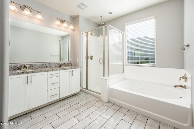 bathroom with a garden tub, wood finish floors, visible vents, a stall shower, and double vanity