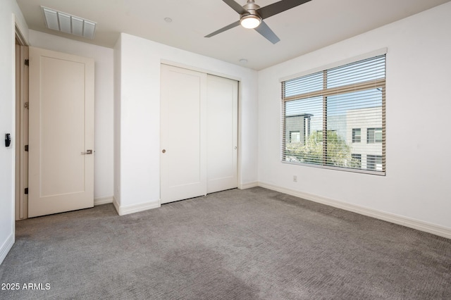 unfurnished bedroom featuring a closet, baseboards, carpet flooring, a ceiling fan, and visible vents