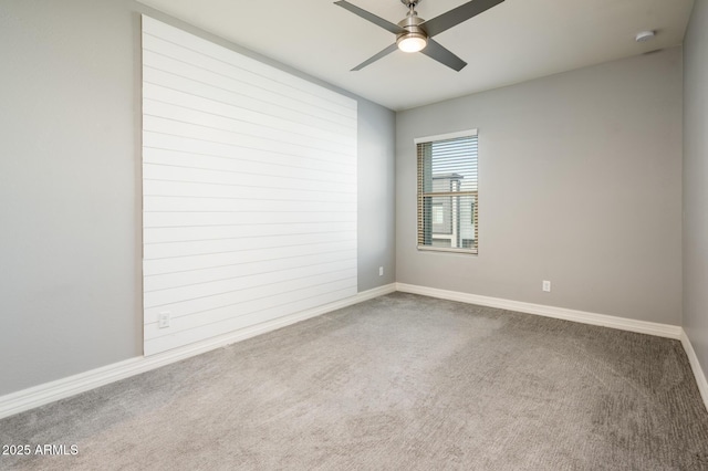 carpeted empty room with baseboards and a ceiling fan