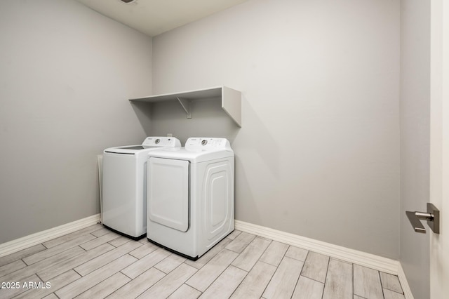 clothes washing area with baseboards, washer and dryer, laundry area, and wood tiled floor
