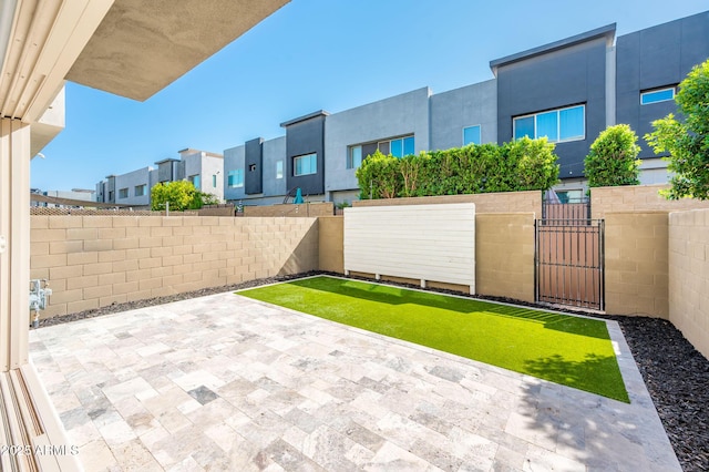 view of yard featuring a patio area, a residential view, fence private yard, and a gate