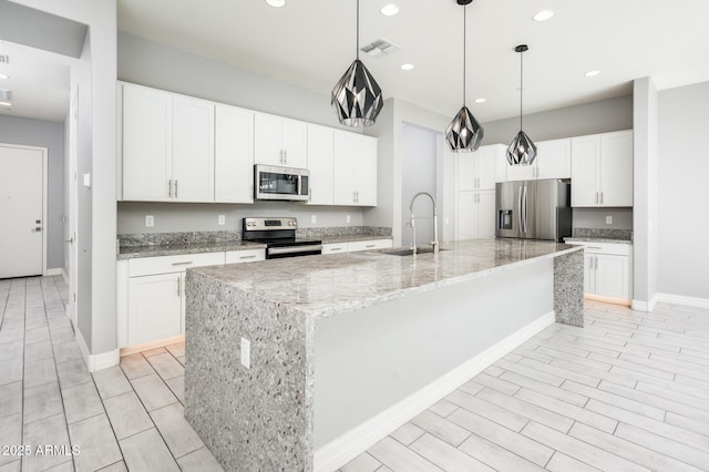 kitchen featuring visible vents, white cabinets, a sink, stainless steel appliances, and a large island with sink