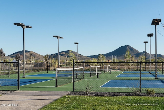 view of tennis court with a mountain view and fence