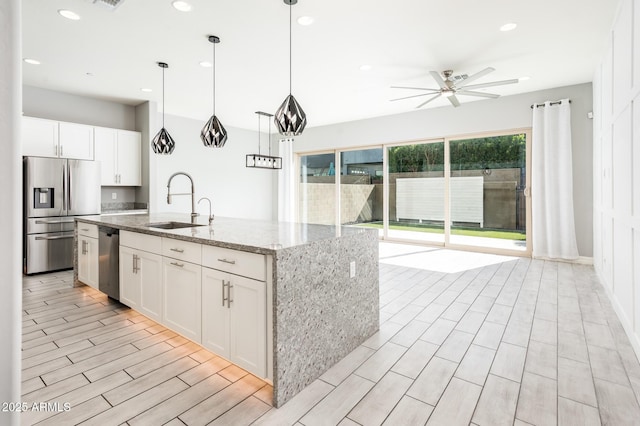 kitchen with a sink, a ceiling fan, white cabinetry, and stainless steel appliances