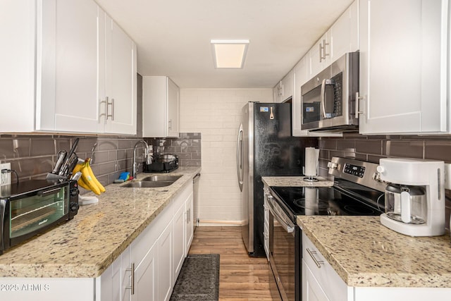 8532 E Portland St, Scottsdale, AZ 85257 - kitchen featuring appliances with stainless steel finishes, light wood-style floors, white cabinets, tasteful backsplash, and light stone countertops