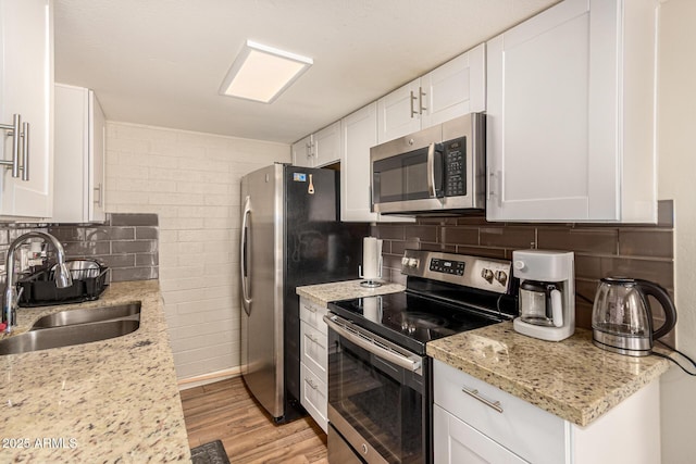 8532 E Portland St, Scottsdale, AZ 85257 - kitchen featuring stainless steel appliances, white cabinetry, tasteful backsplash, and light wood-style flooring
