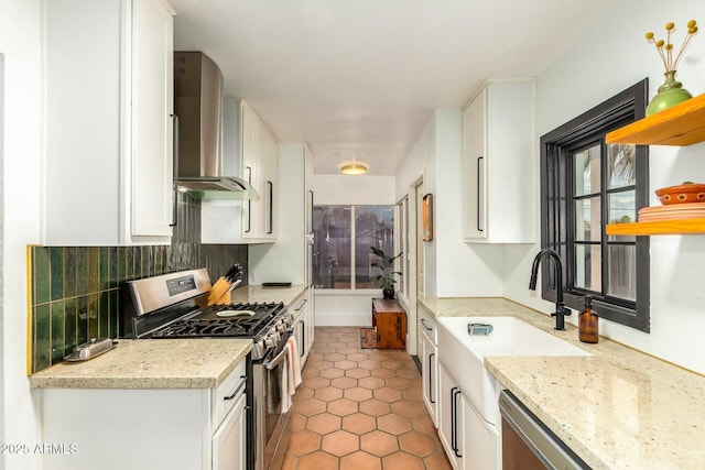 kitchen with wall chimney range hood, appliances with stainless steel finishes, light stone countertops, white cabinets, and decorative backsplash