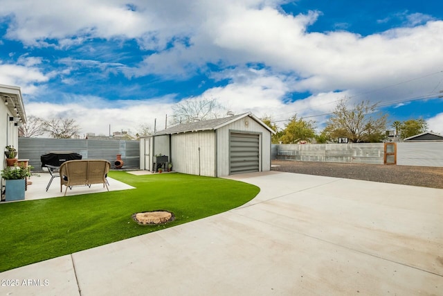 view of yard featuring a garage, an outbuilding, and a patio area