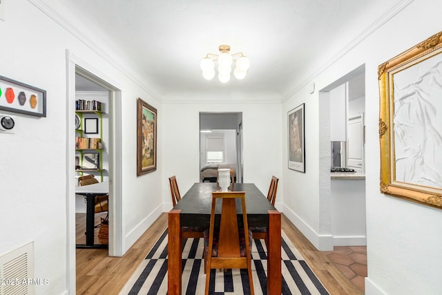 dining area with an inviting chandelier, ornamental molding, and light hardwood / wood-style floors