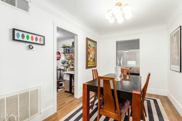 dining space with crown molding, a chandelier, and light hardwood / wood-style flooring