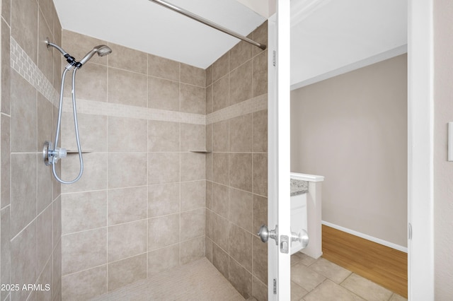 full bath featuring tiled shower, baseboards, and tile patterned floors