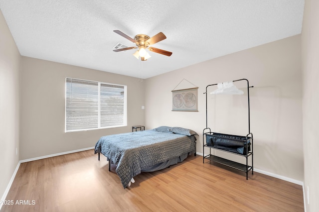 bedroom featuring a textured ceiling, ceiling fan, visible vents, baseboards, and light wood-type flooring