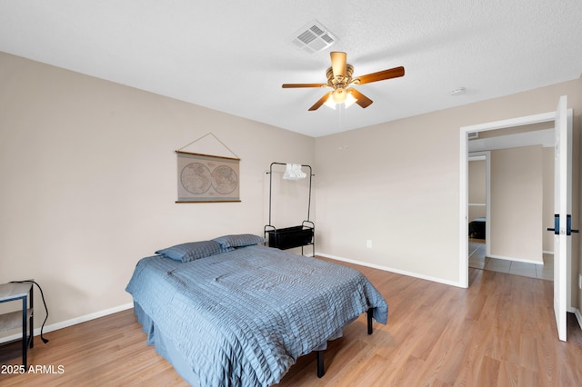 bedroom featuring light wood finished floors, baseboards, visible vents, and a ceiling fan