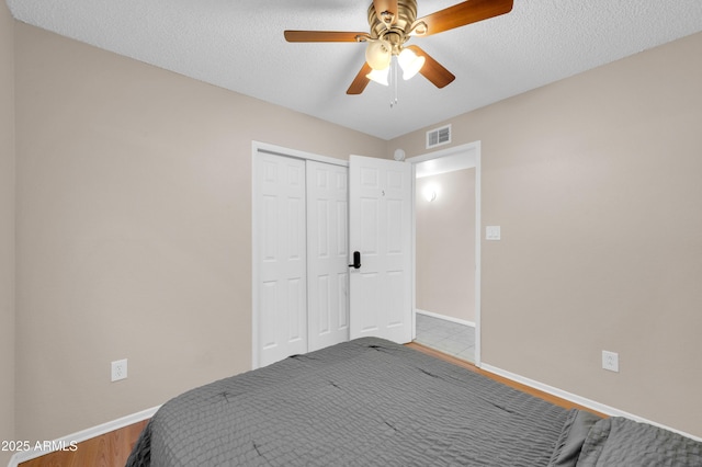 bedroom featuring baseboards, visible vents, a ceiling fan, a textured ceiling, and a closet