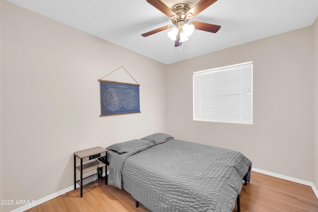 bedroom with a textured ceiling, light wood finished floors, a ceiling fan, and baseboards