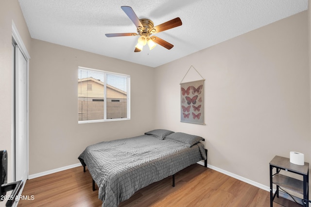 bedroom featuring a textured ceiling, a closet, wood finished floors, and baseboards