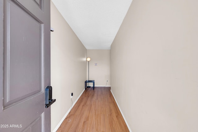 washroom featuring light wood-style floors, baseboards, and a textured ceiling